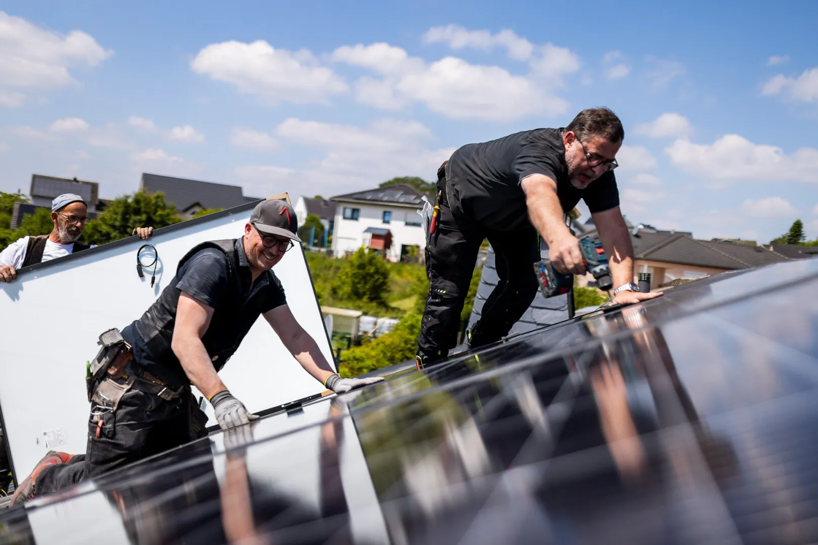 Zwei Männer installieren ein Solarpanel auf einem Dach.